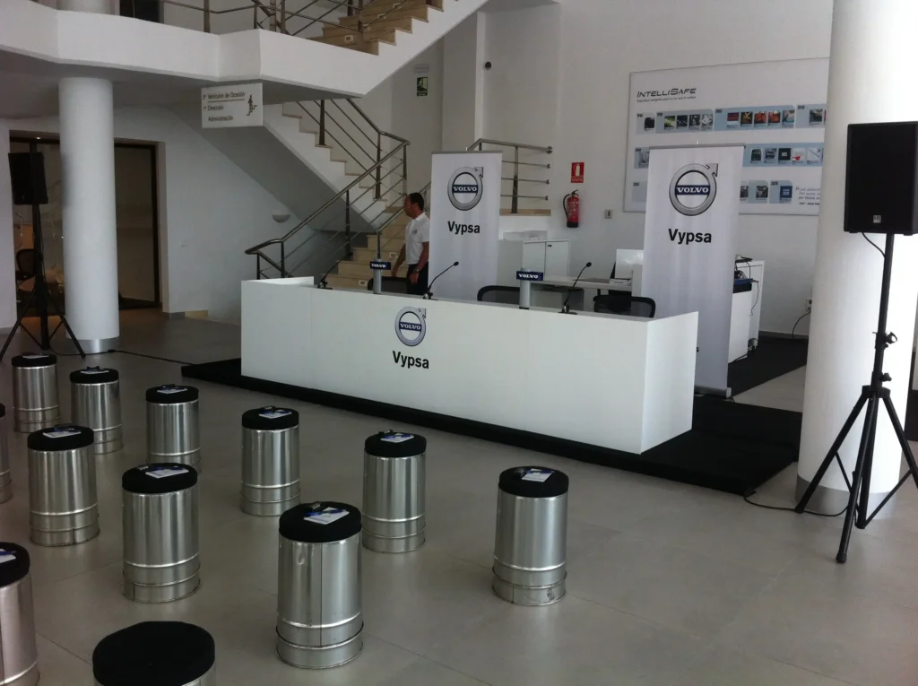 A raised presentation platform with an HK Audio speaker on a stand, delivered by Malaga Event Gear for a Volvo dealership event in Malaga.