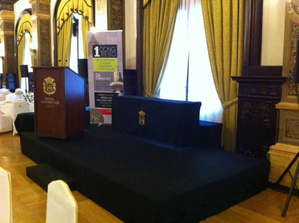 A raised staging platform and podium delivered by Malaga Event Gear at Hotel Alfonso XIII in Malaga, set up for a medical congress.