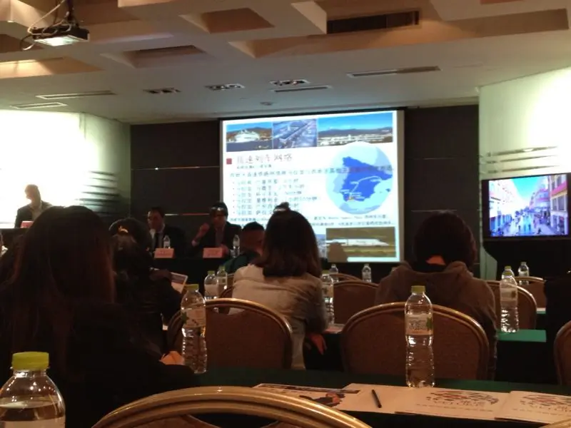 Setup for a MICE event in Malaga with a podium, professional lighting, sound equipment, a large screen and a projector.