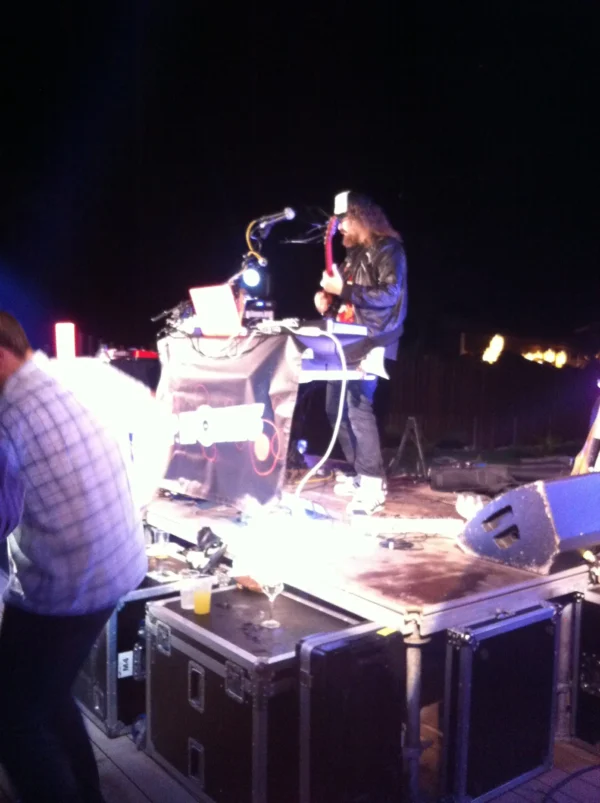 A live DJ and guitarist performing on stage with professional audio and lighting equipment during an outdoor event in the province of Malaga